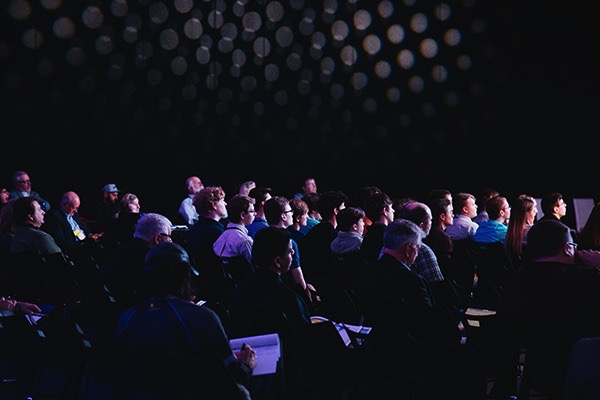 Audience members listening intensively to a seminar on employee financial wellness.